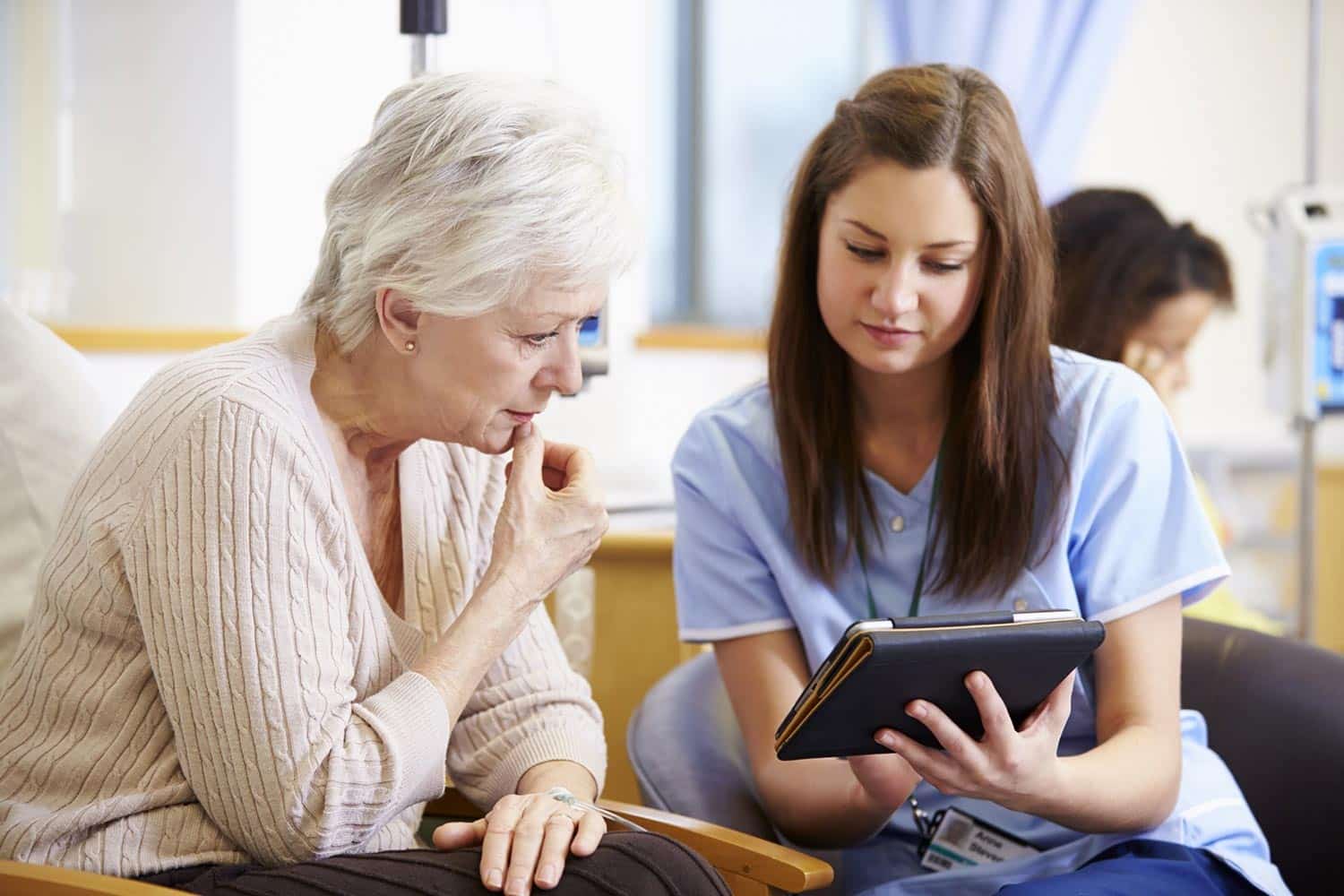 Woman in scrubs helping an elderly patient